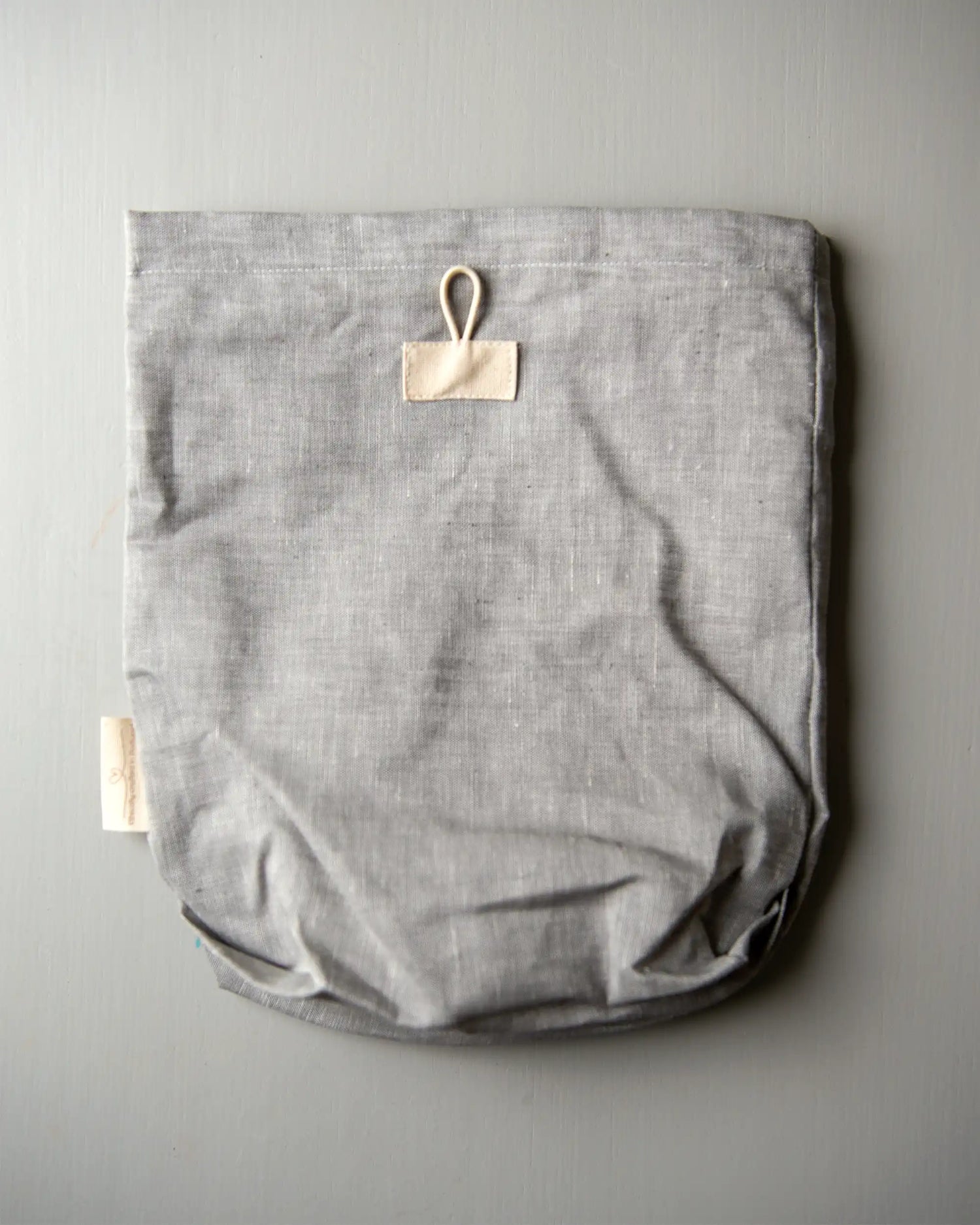 En handsydd ljusgrå förvaringspåse i linne.