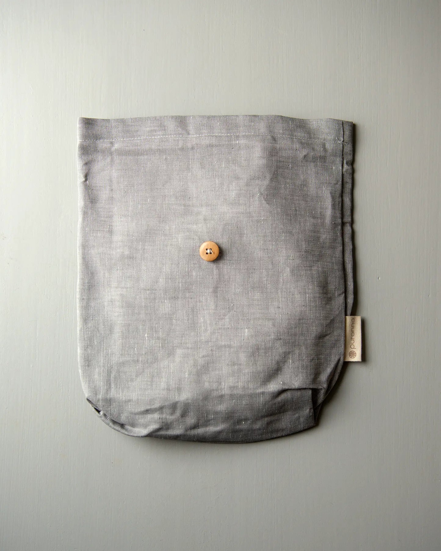 En handsydd grå väska i linne.