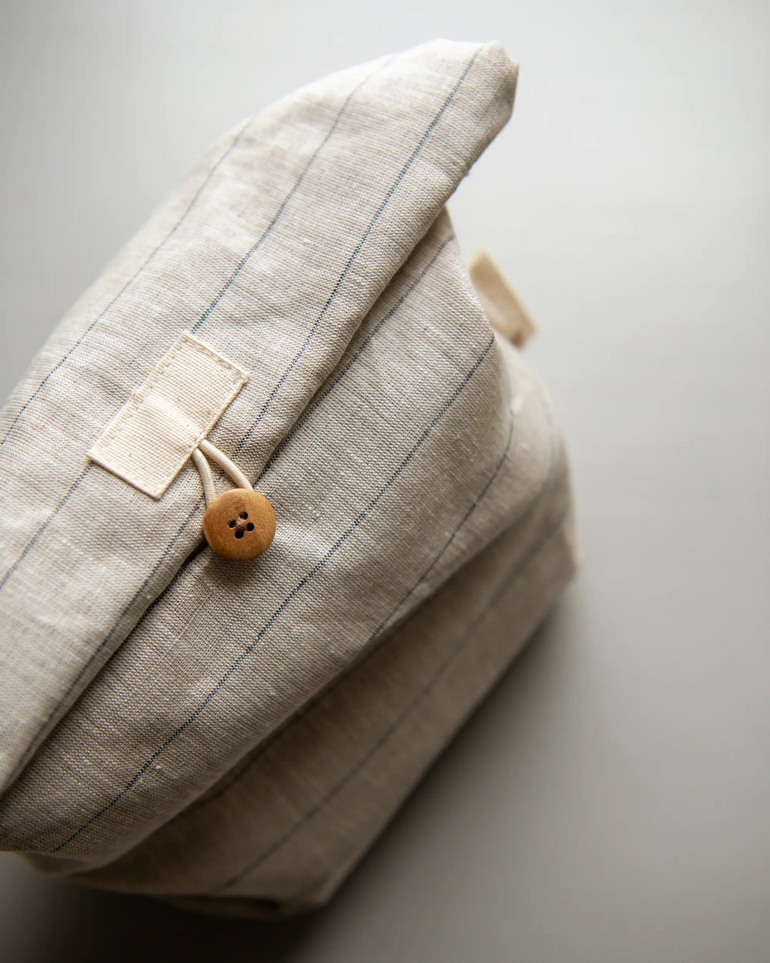 En handsydd randig lunchpåse i linne med en brun knapp. 