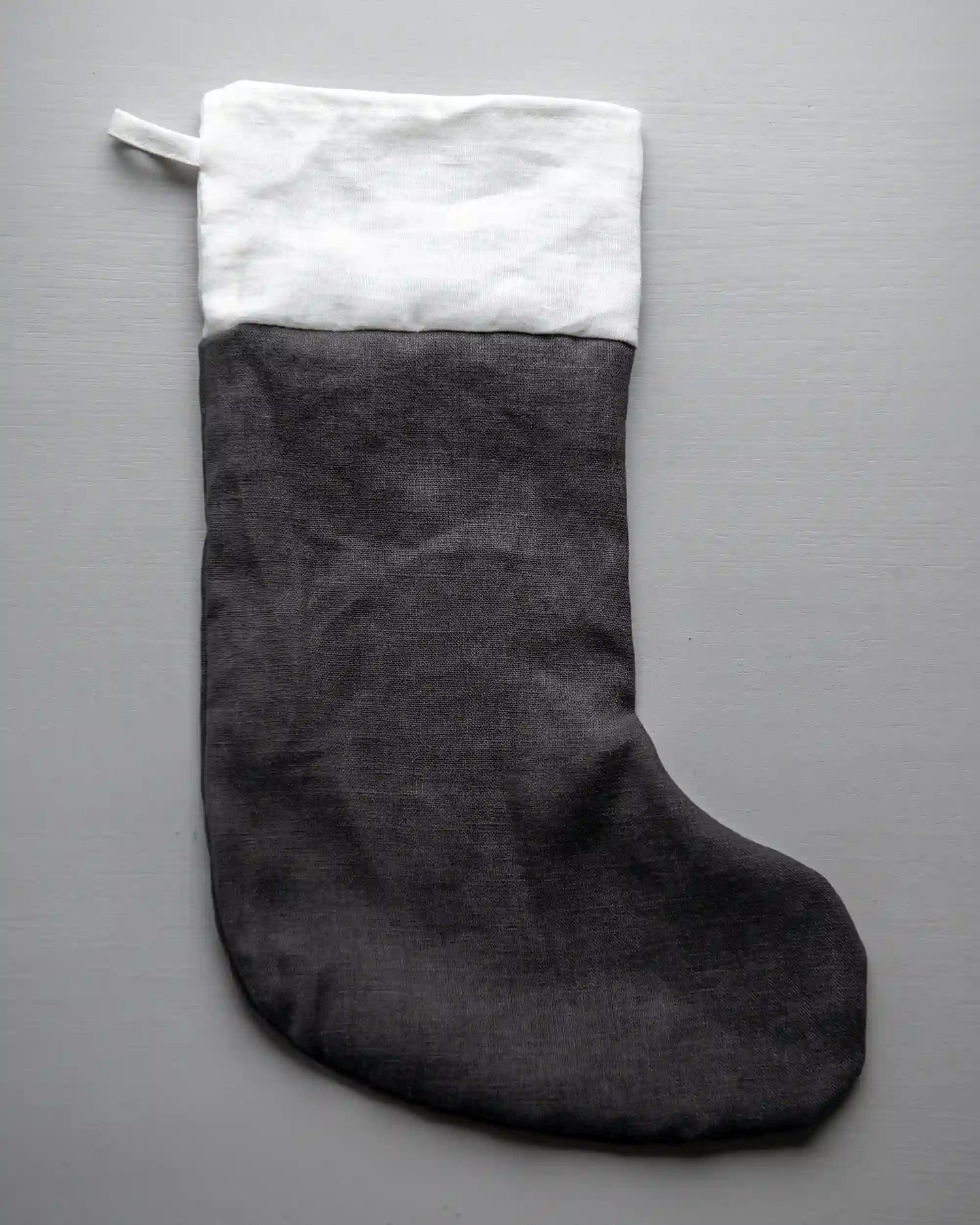 En mörkgrå handsydd julstrumpa i linne med vit kant. 