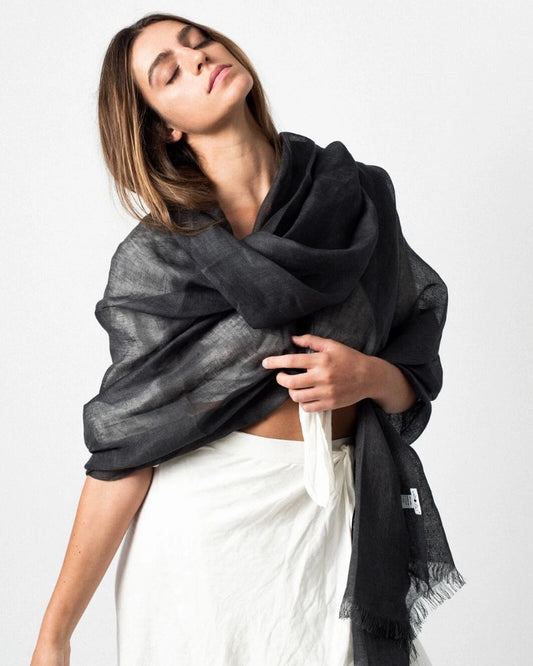 En handvävd linnehalsduk i mörkgrå med fransar.