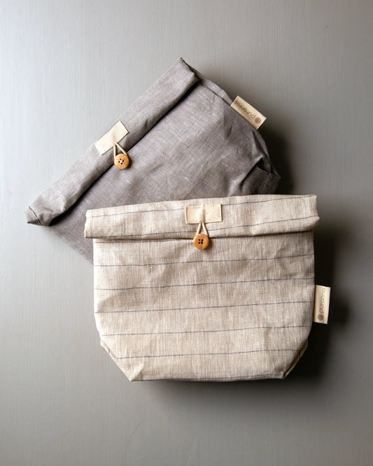 Två stycken lunchpåsar i grå och beige linne med dekorativ knapp som man stänger de med.