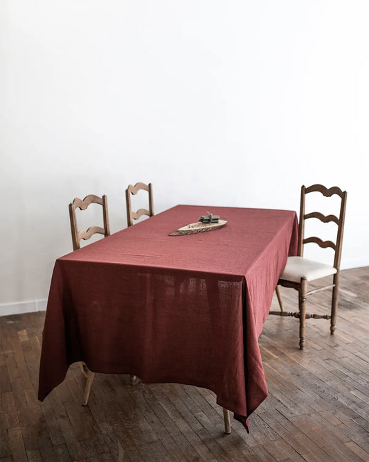 En rektangulär röd duk i linnetyg ligger över ett litet matbord. 