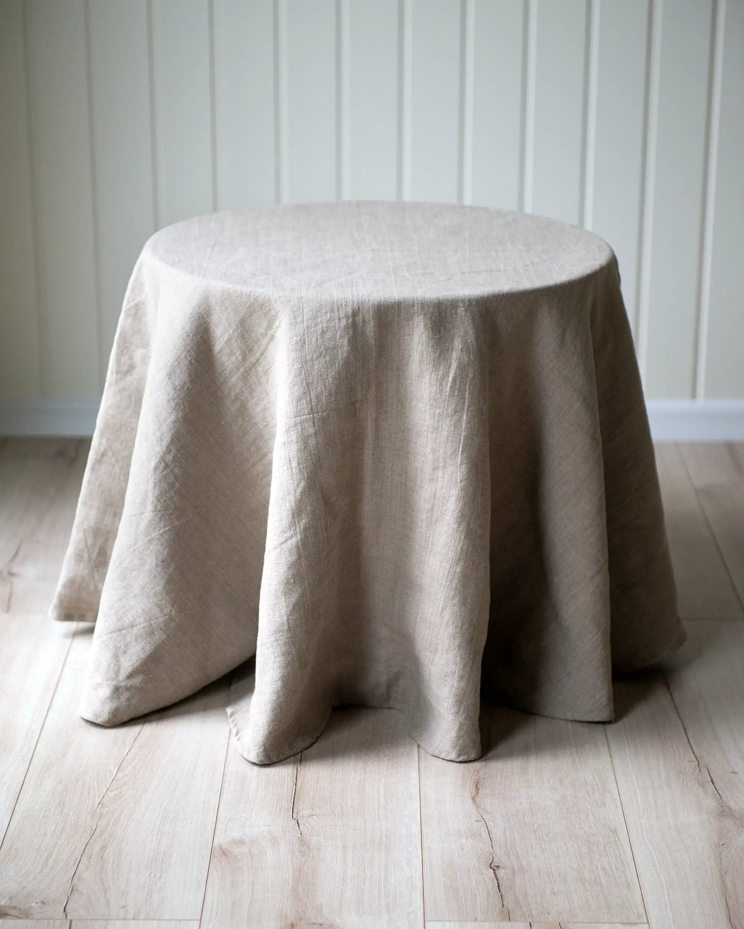 En rund handsydd linneduk i beige.