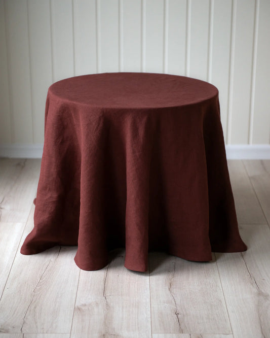 Ett runt bord med en handsydd rund duk i rött linnetyg.