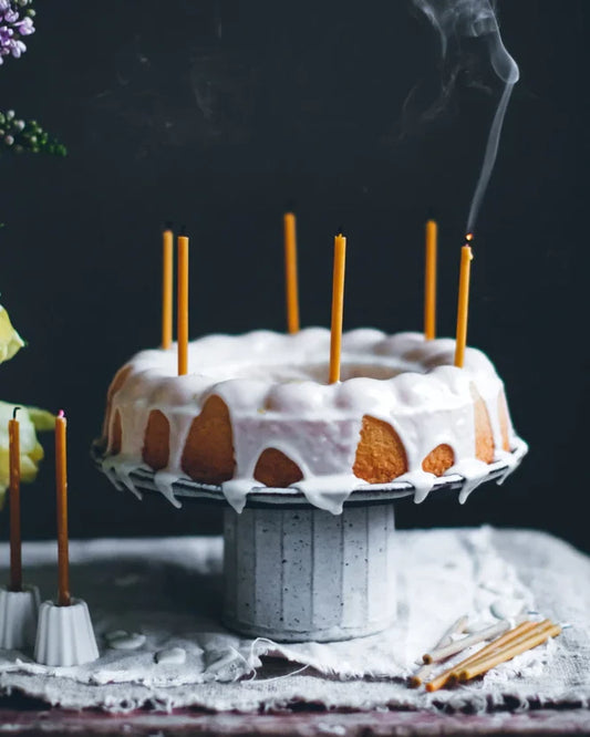 Smala tårtljus i bivax sitter i en tårta som står på ett bord.