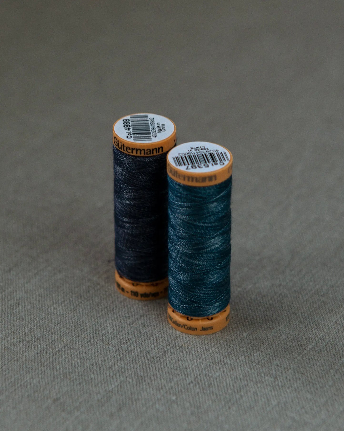 Två trådrullar i olika nyanser för lagning av jeans.