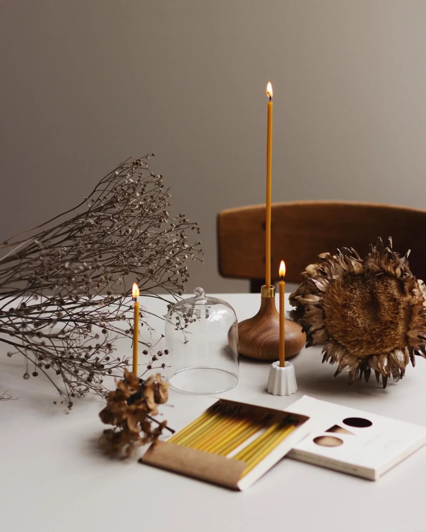 Olika handgjorda ljusstakar i naturmaterial står på ett bord med bivax ljus. 