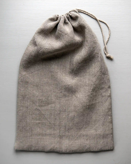 En handsydd brödpåse i naturell linne som har dragits ihop med ett tunt band.   