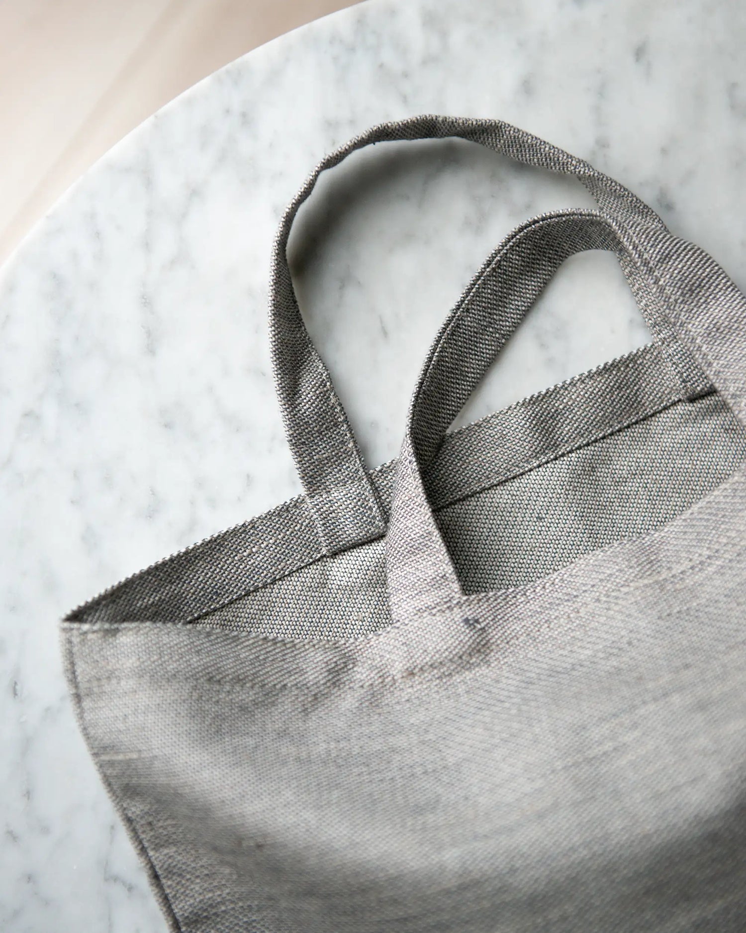 Handtagen på en handsydd grå tygpåse i 100% linne. 