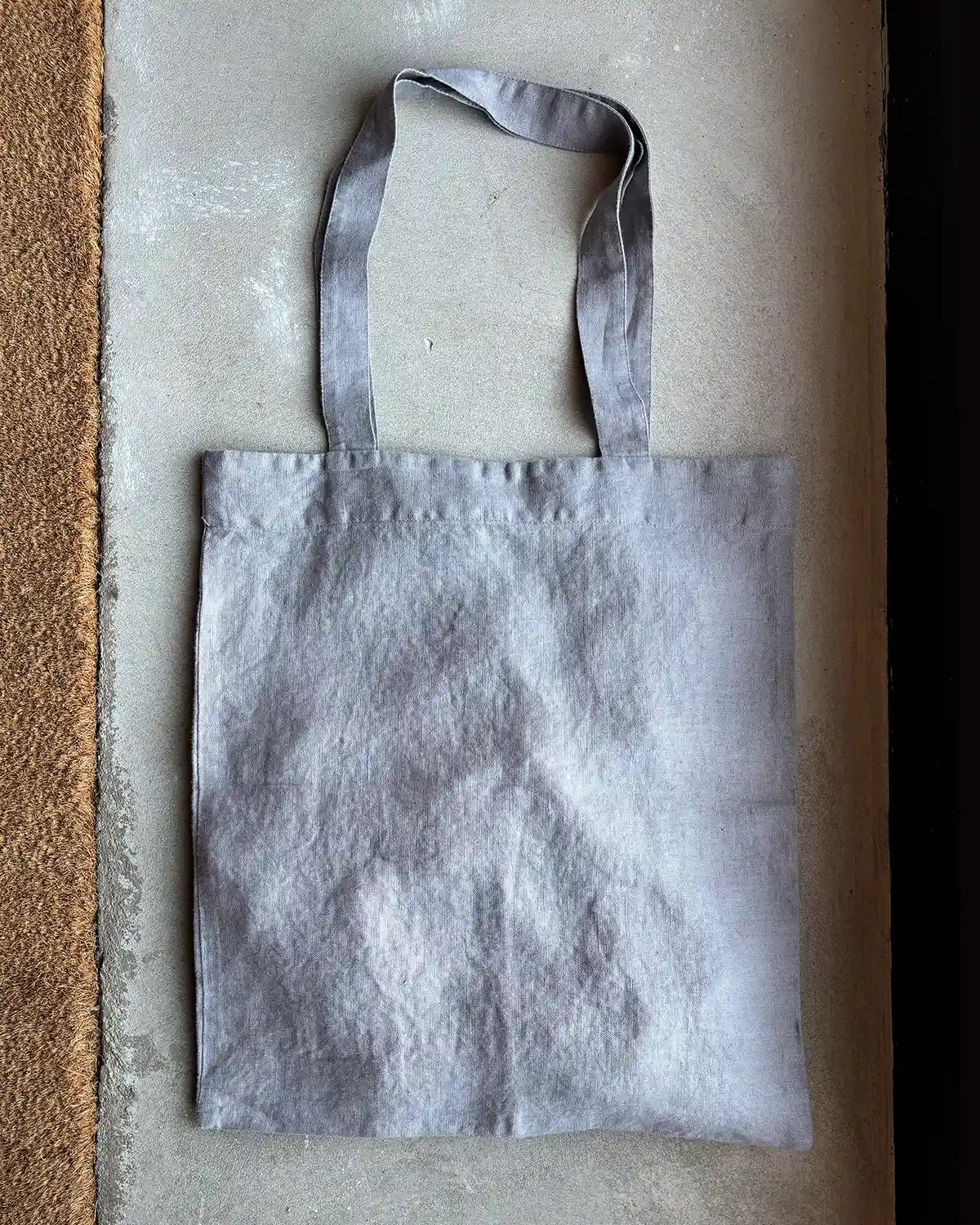 En ljusgrå tygväska med långa handtag