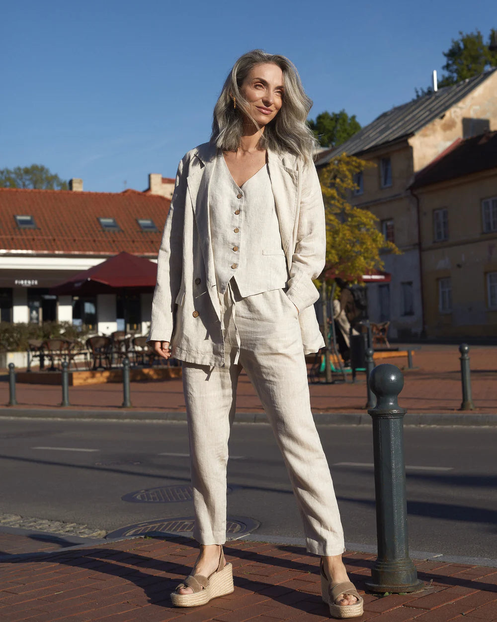 Modellen bär en beige linnebyxa i ankellängd med snöre och resår i midjan.