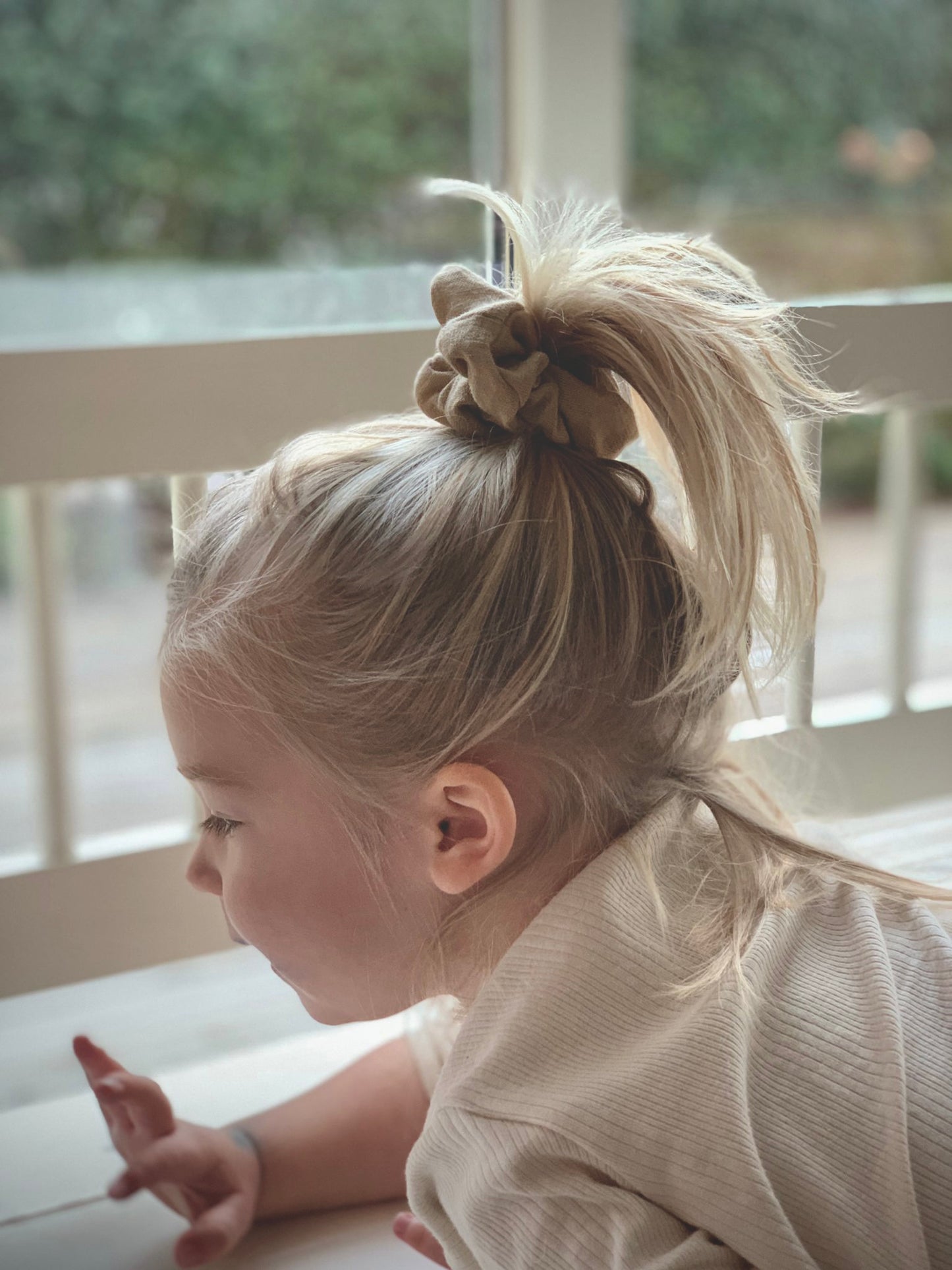 Liten flicka bär handgjord beige scrunchie. 