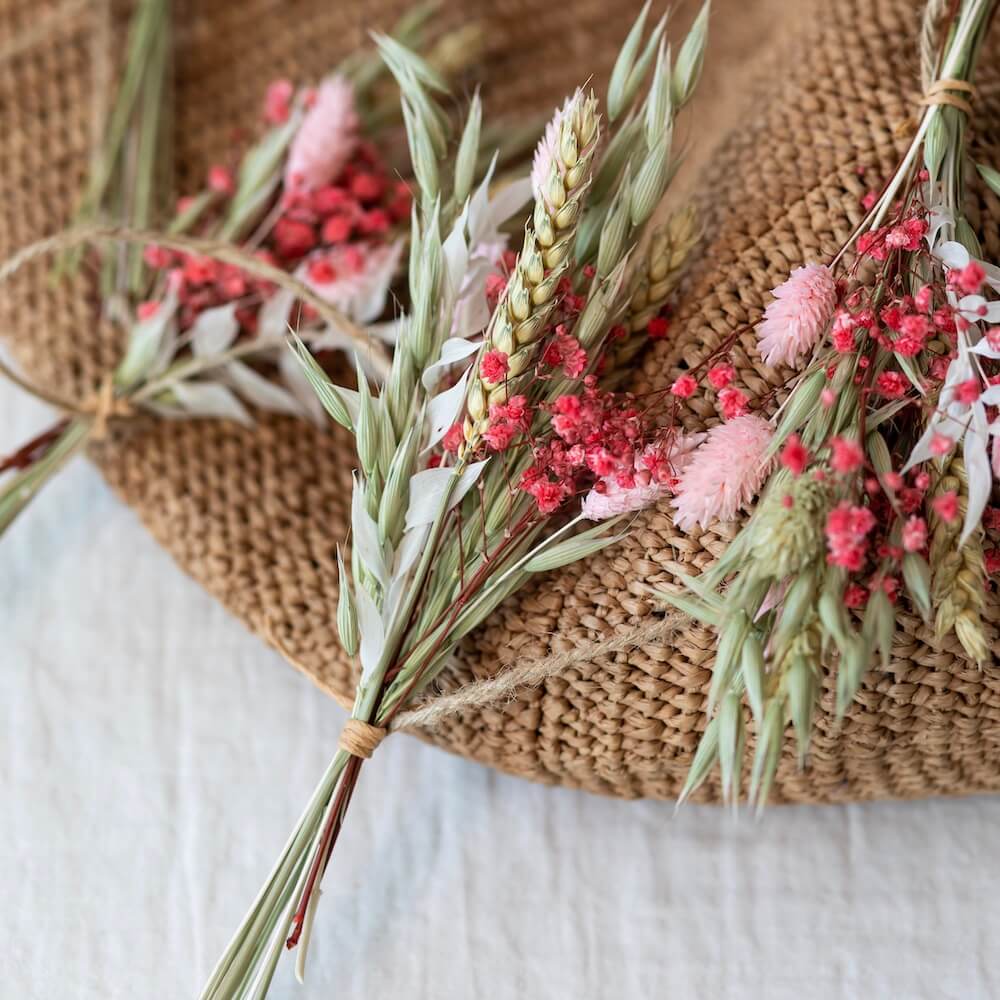 Torkade blommor o små buketter ligger på ett bord.