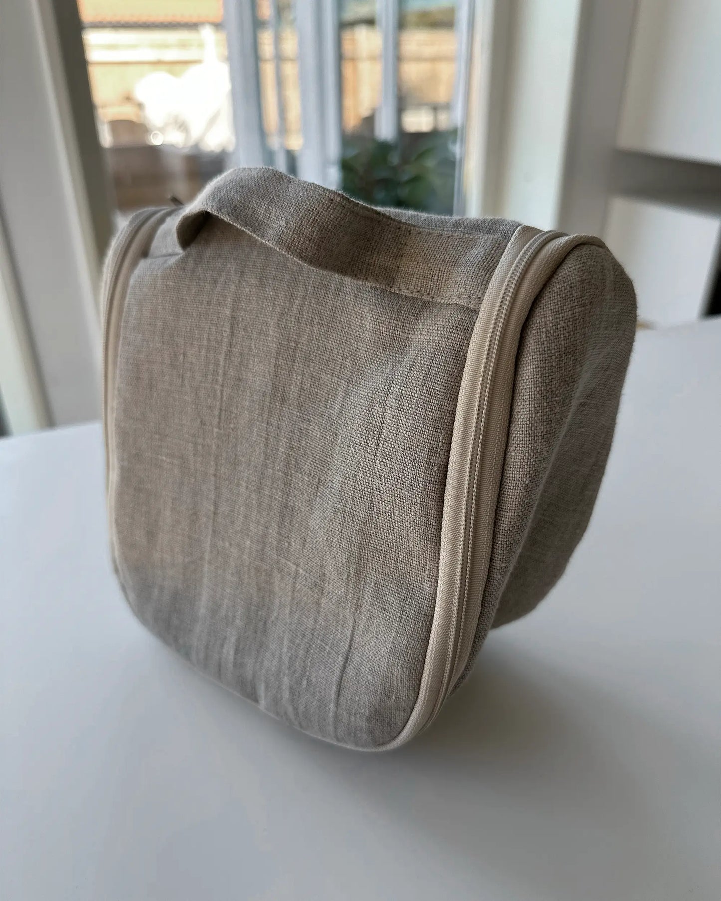 En beige nesecsär i stentvättat linnetyg med dragkedja och handtag. 
