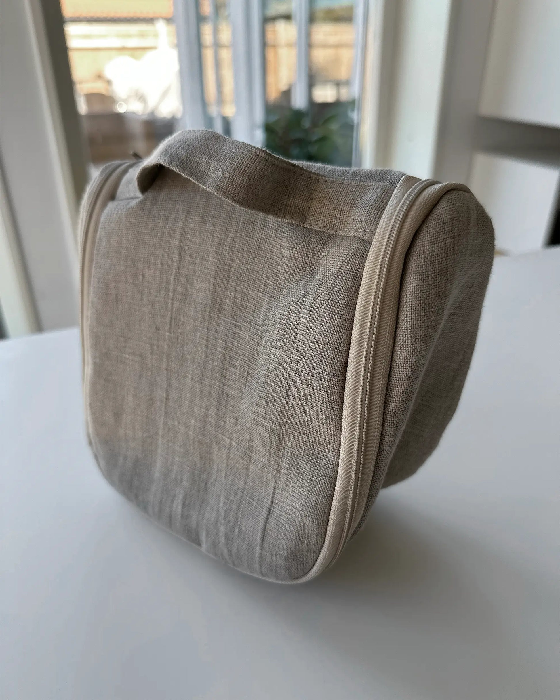 En beige nesecsär i stentvättat linnetyg med dragkedja och handtag. 