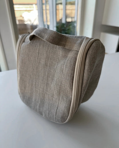 En beige nesecsär i stentvättat linnetyg med dragkedja och handtag. 