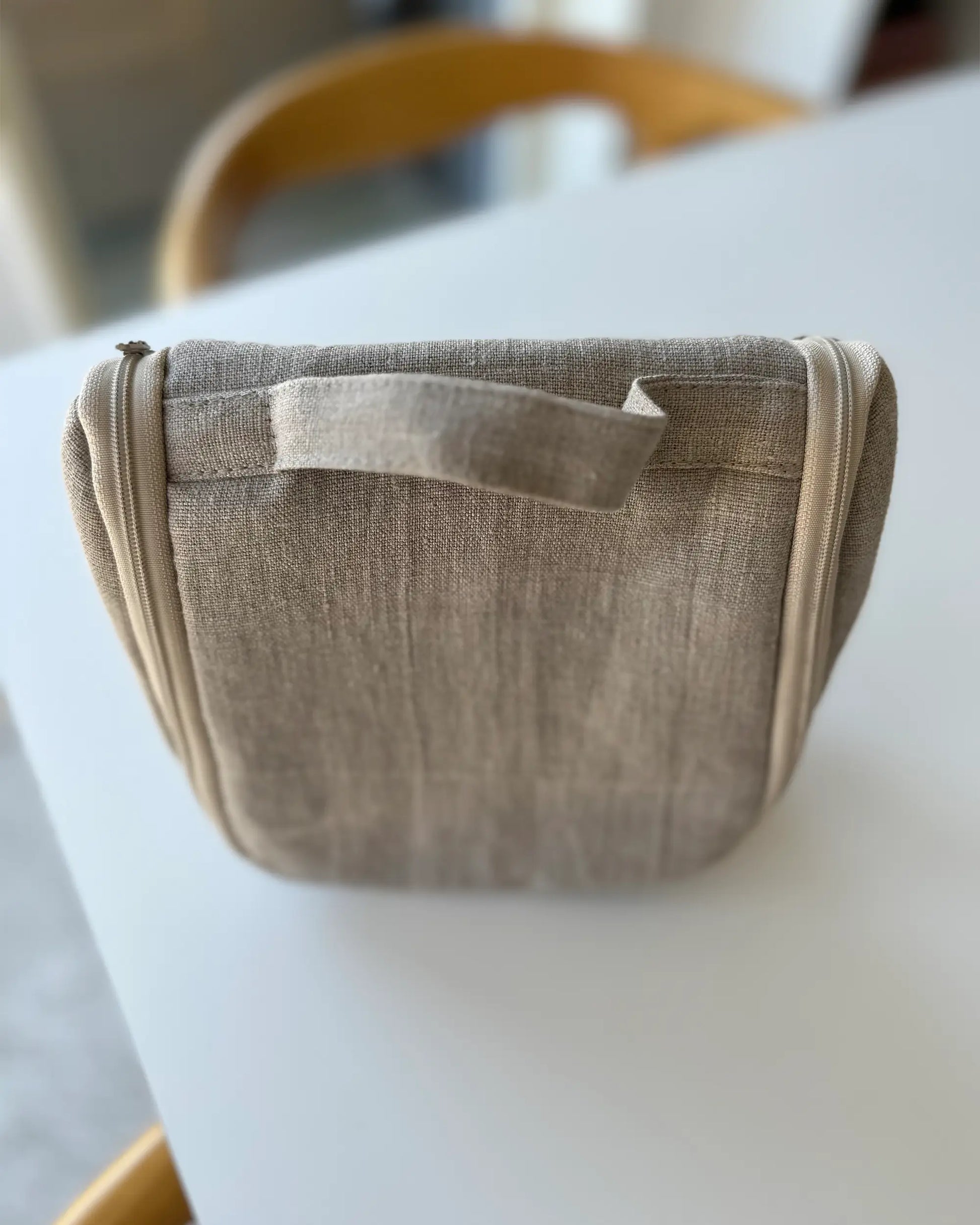 En handsydd sminkväska i stentvättat linnetyg med handtag. 