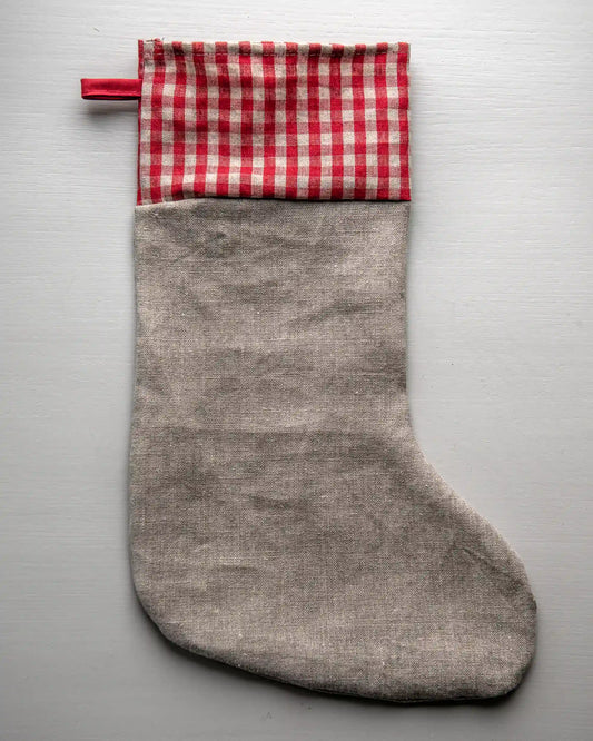 En julstrumpa i naturell linne med en vit rutig kant och ögla.